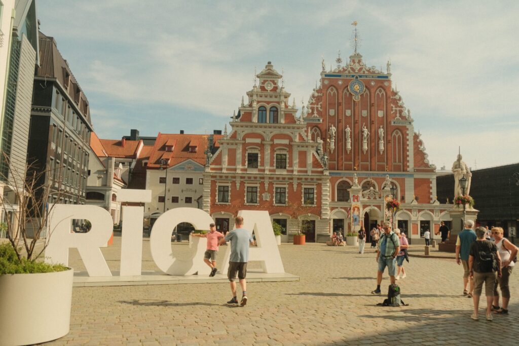 As Melhores Cidades para Trabalhar na Letônia em 2026 Vista aérea moderna de Riga, capital da Letônia, com o rio Daugava e edifícios corporativos iluminados ao entardecer.