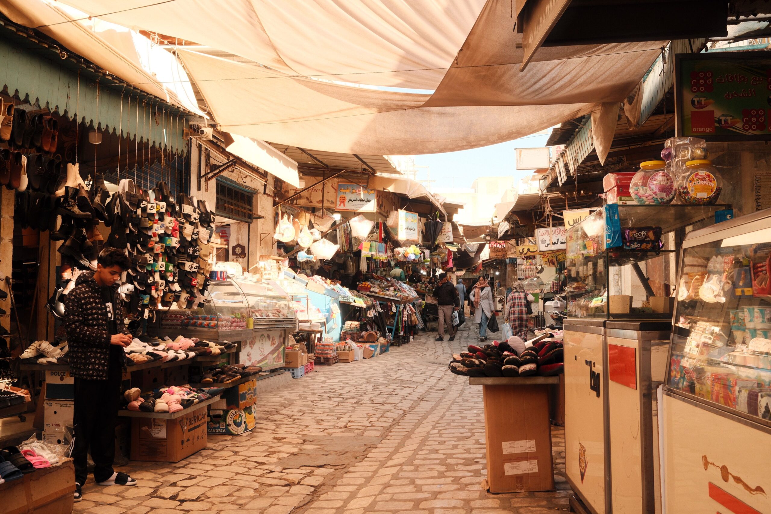 Medina de Túnis com lojas e turistas caminhando entre as ruelas históricas
