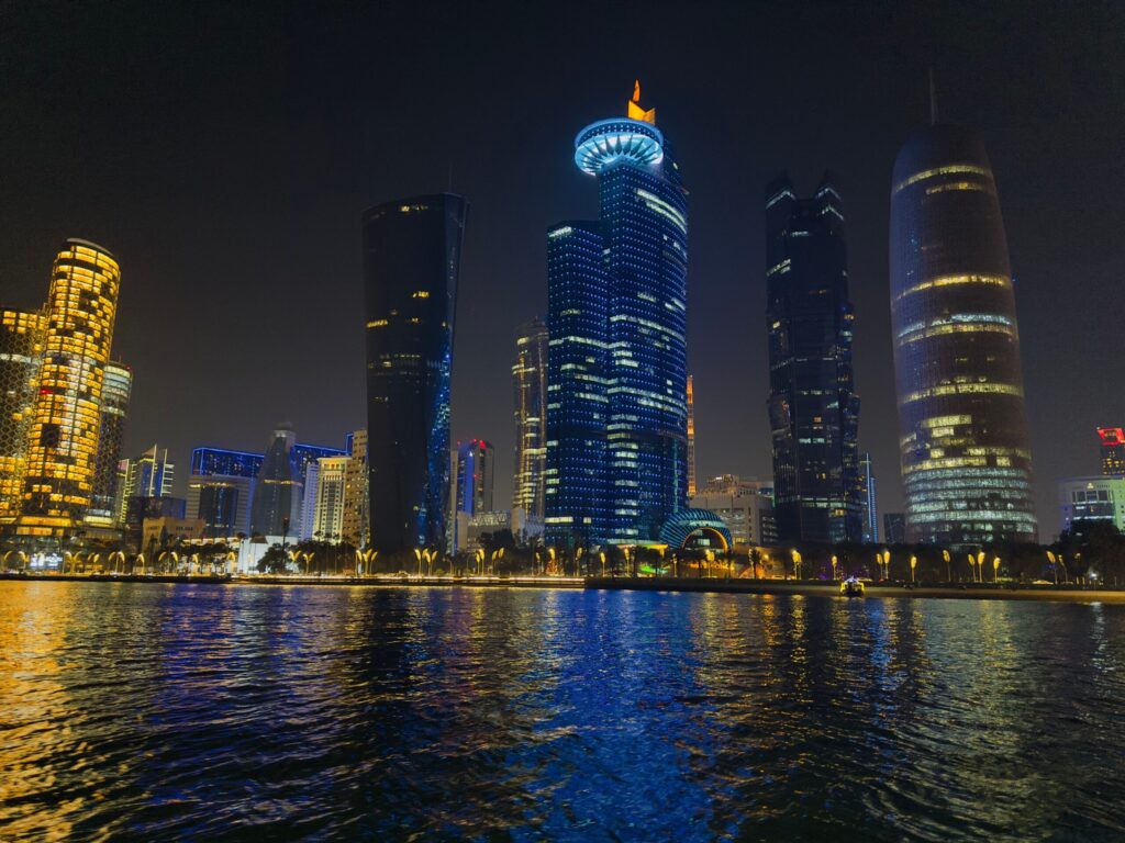 Viajar para o Catar em 2026: Roteiro, Requisitos e Dicas Úteis Eu sorrindo enquanto organizo meus roteiros de viagem e anotações sobre o Catar em uma cafeteria charmosa em Doha.
