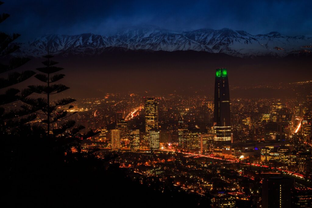Quanto Custa Viajar para o Chile em 2026? Valores Reais e Gastos Paisagem deslumbrante da Cordilheira dos Andes com neve ao fundo e um guia de turismo aberto ao lado de notas de pesos chilenos.