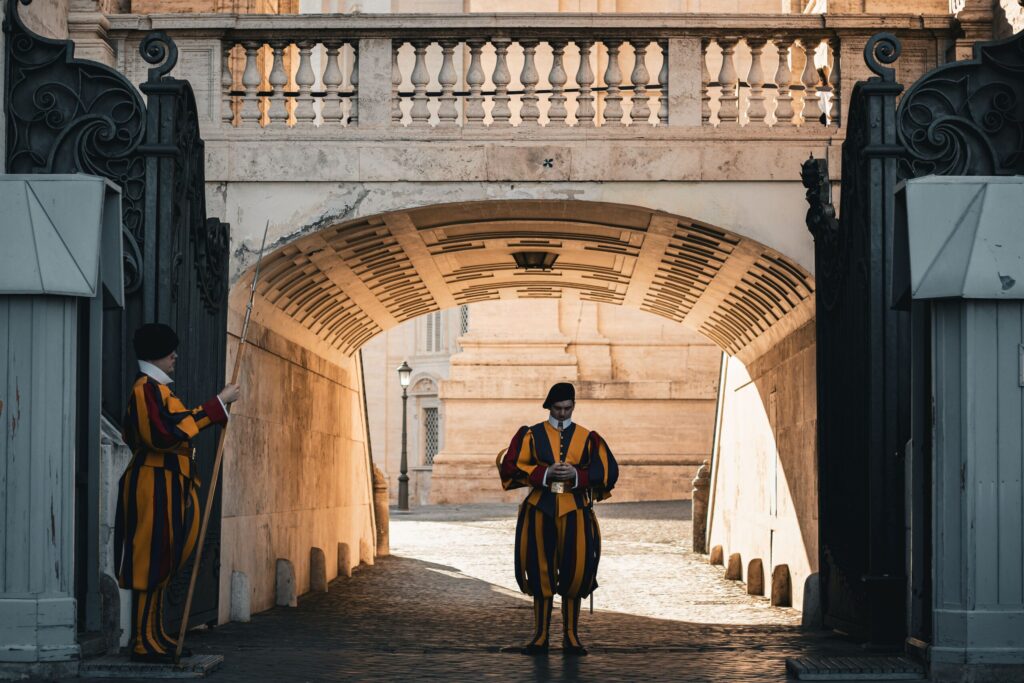 Salário Mínimo no Vaticano em Reais (2026): Quanto se Ganha LÁ? Calculadora financeira e notas de Euro dispostas sobre um guia de inserção profissional em instituições europeias.