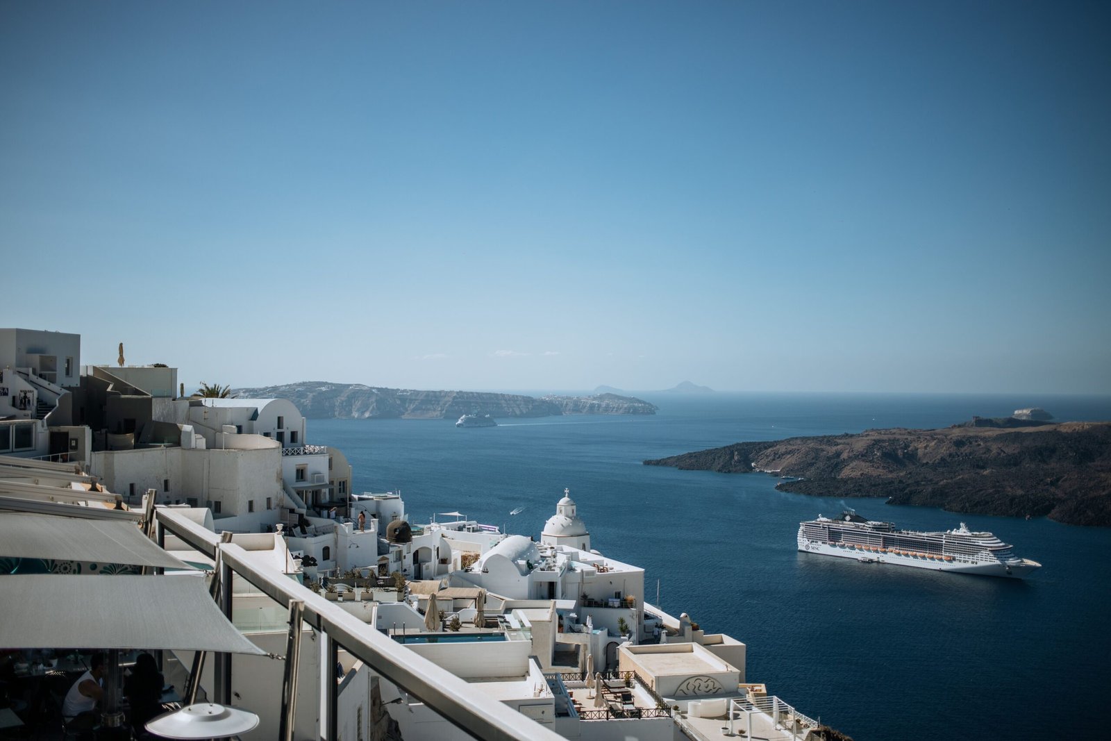 Melhores itinerários de cruzeiro pelas ilhas gregas em 2026 Ilhota vulcânica e caldeira de Santorini vistas de um navio de cruzeiro