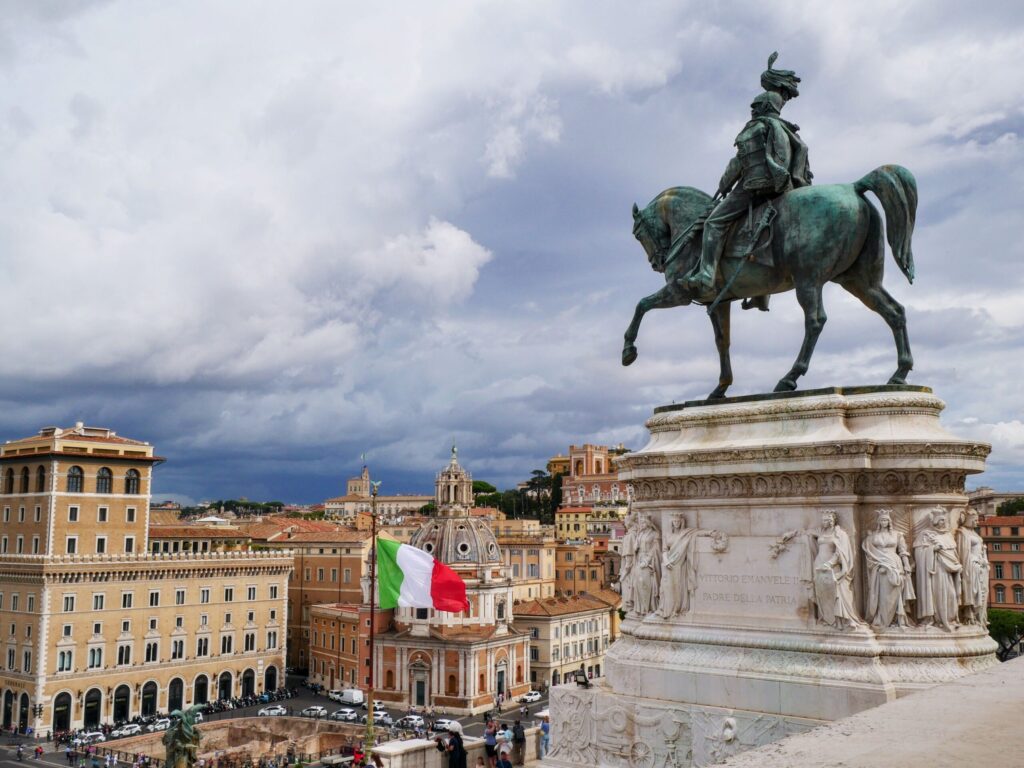 Vaticano ou Roma: Onde Vale Mais a Pena em 2026? Comparativo Notas de Euro e moedas espalhadas sobre um mapa turístico detalhado da Itália ao lado de uma calculadora.