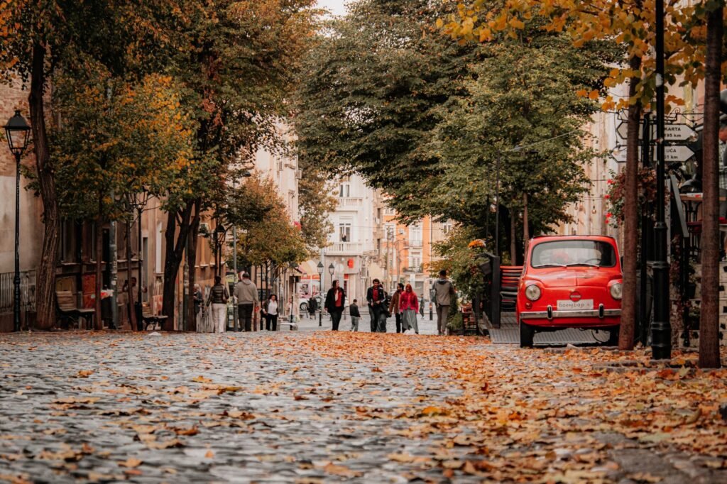 Outono na Europa em 2026: Quando Começa, Clima e Melhores Destinos Mala de viagem aberta com casacos leves, cachecóis, botas e trench coat para o clima de outono na Europa.