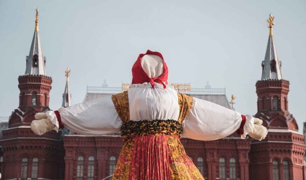 Espantalho ou boneca gigante em trajes folclóricos tradicionais russos durante celebração cultural ao ar livre.