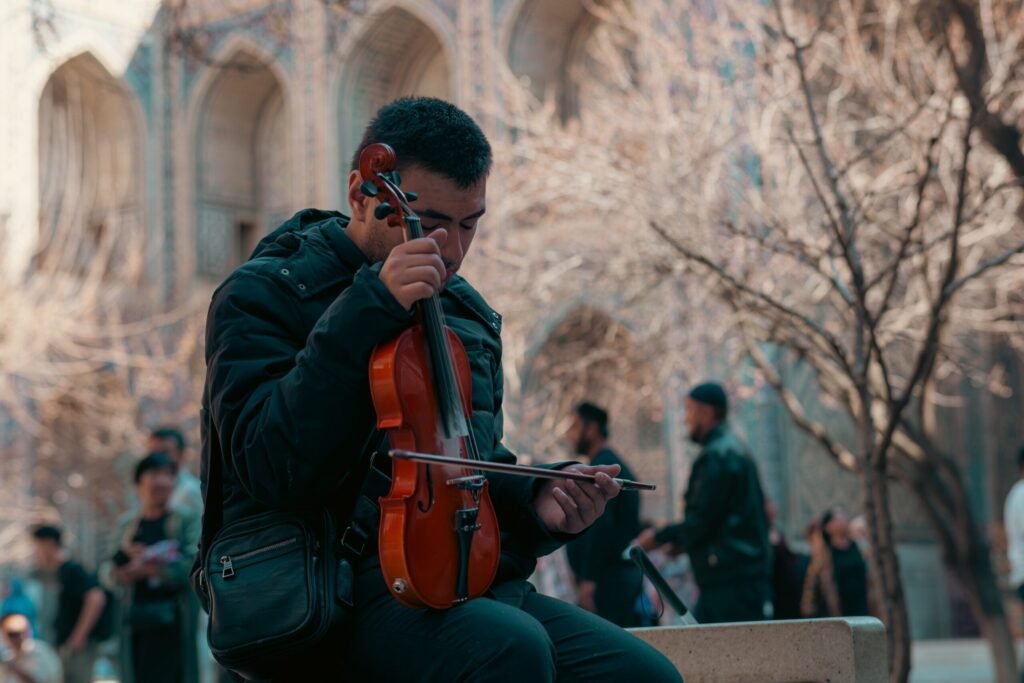 Salário Mínimo no Uzbequistão em Reais (2026): Quanto É? Jovem músico a tocar violino nas ruas de uma cidade histórica no Uzbequistão.