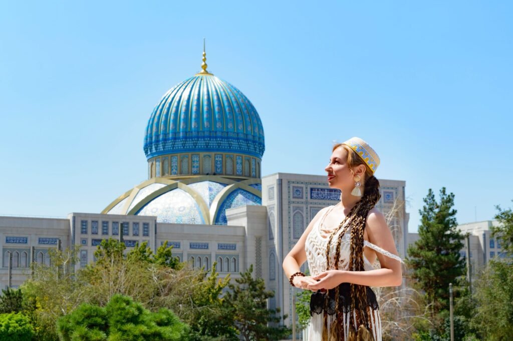 Cartão Nomad no Uzbequistão em 2026: Guia Completo Turista em trajes claros em frente a uma imponente mesquita de cúpula azul sob céu limpo no Uzbequistão.