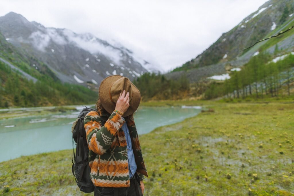 Quanto Custa Viajar para a Rússia em 2026? Guia Completo Turista com mochila observando uma paisagem natural de montanhas e lago na Rússia ao ar livre.